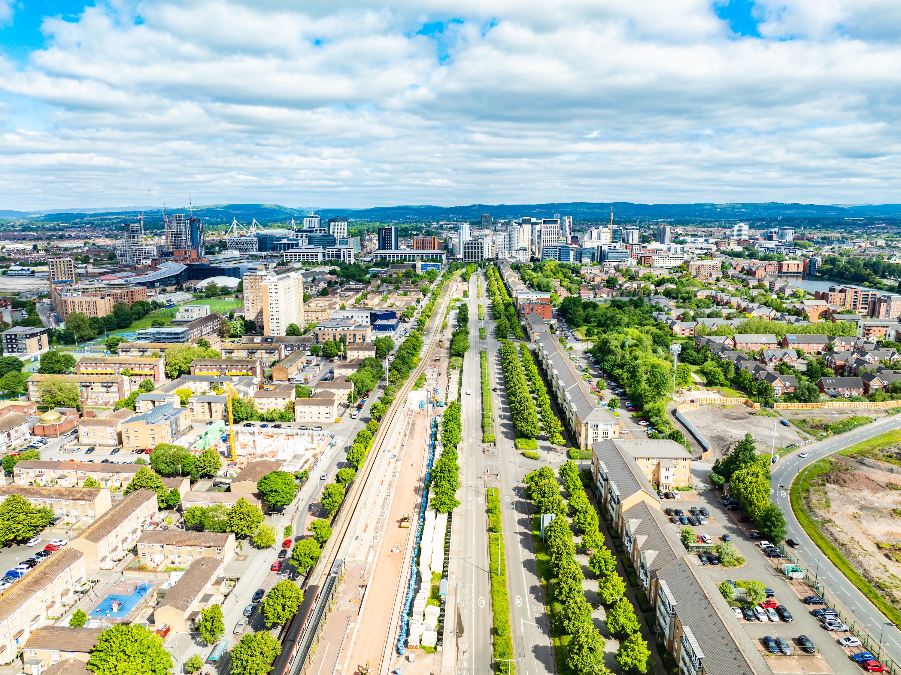 A skyline drone photo of Cardiff looking down a straight road and train track to the Principality Stadium