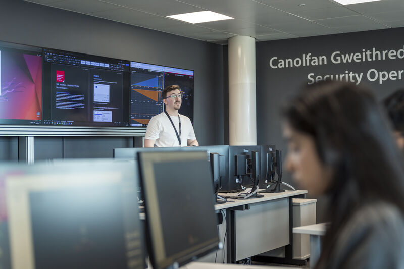 A lecturer speaking to students in a cyber security classroom