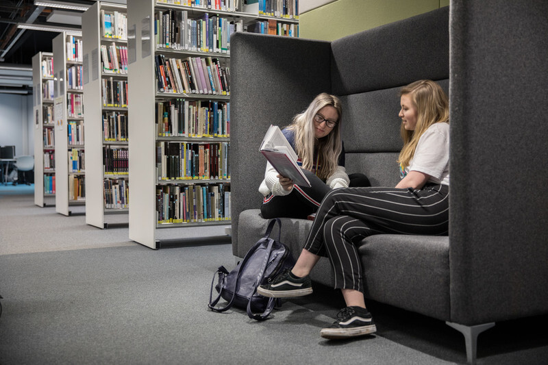 Students sitting in a study pod in the Cardiff campus library.