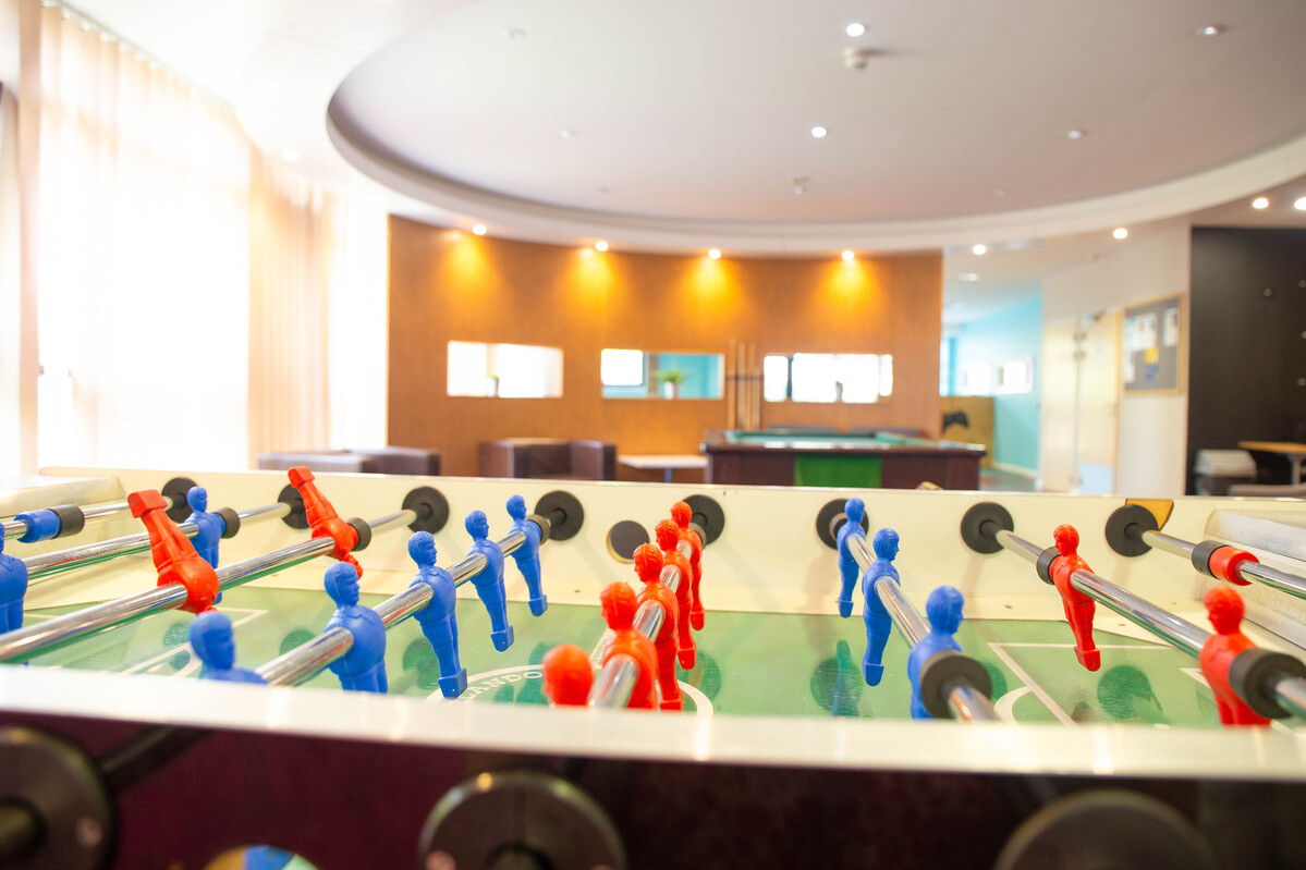 A close up shot of a foosball table set in front of a seated area.