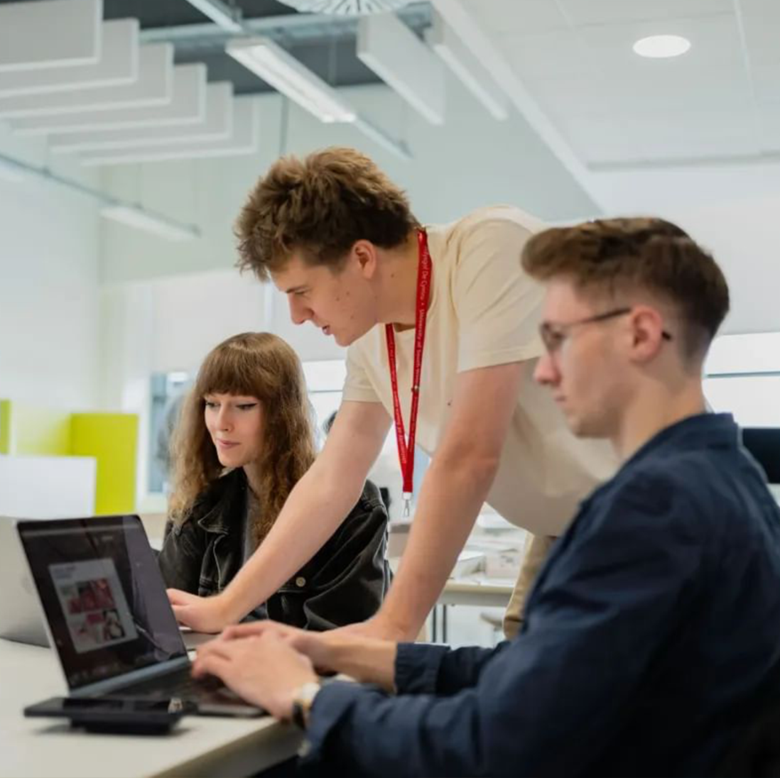 Graphic communication lecturer showing working with two students in the classroom.