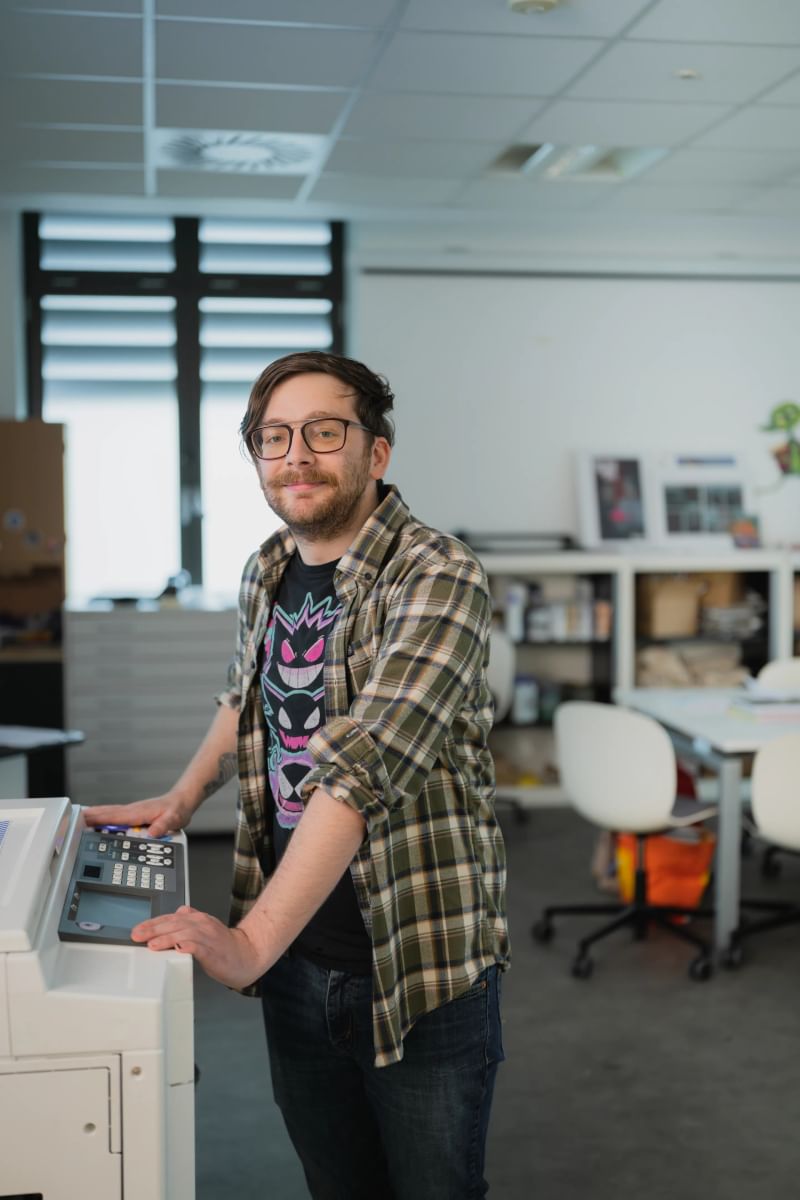 Illustration student standing next to a printer on campus
