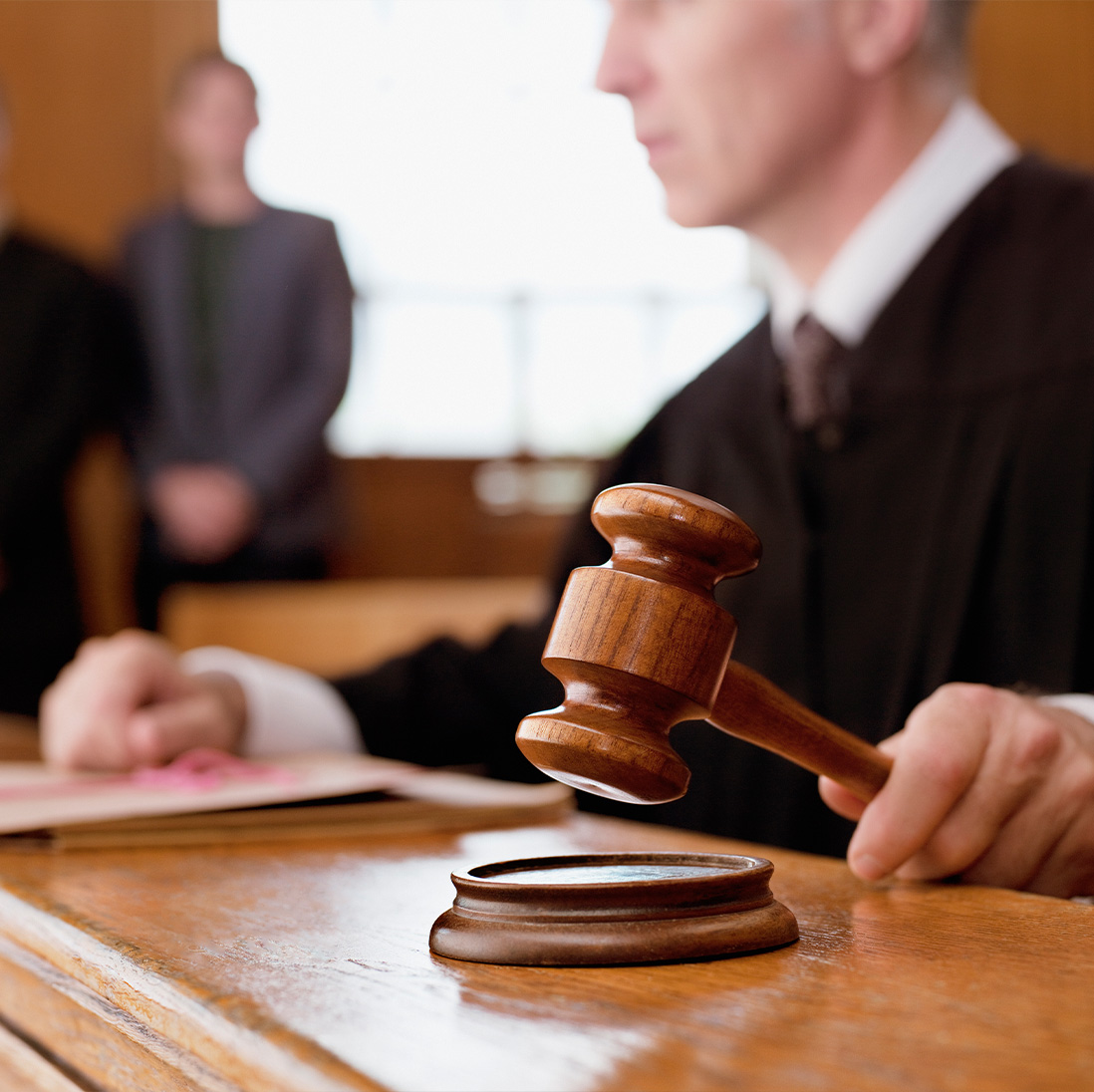 Am American judge uses a gavel hammer to strike a wooden pad at the judges bench in a courtroom