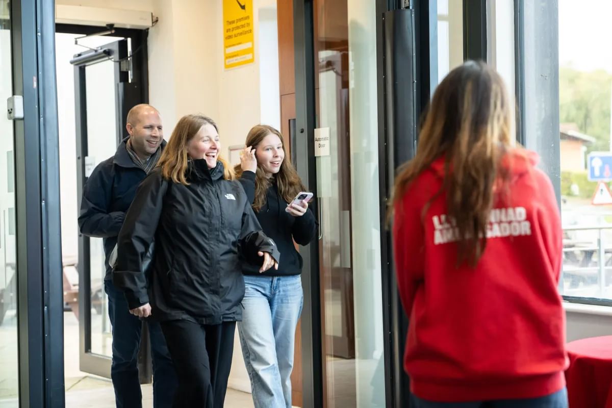 A student ambassador welcoming a smiling family at a USW Open Day.