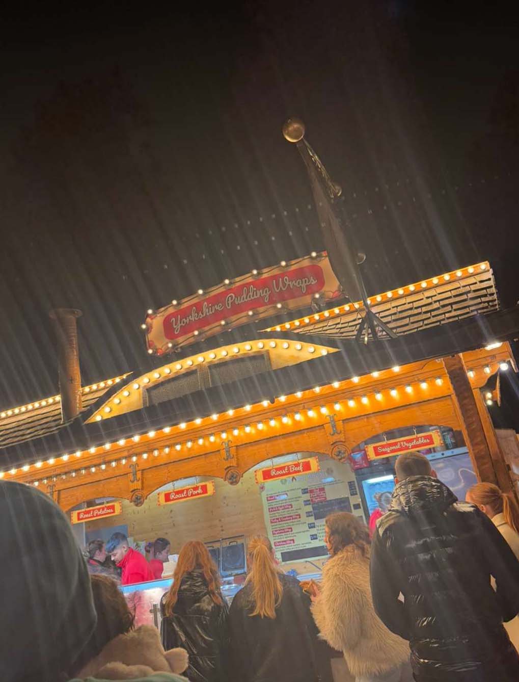A crowd of people lines up at a yorkshire pudding wrap stall.