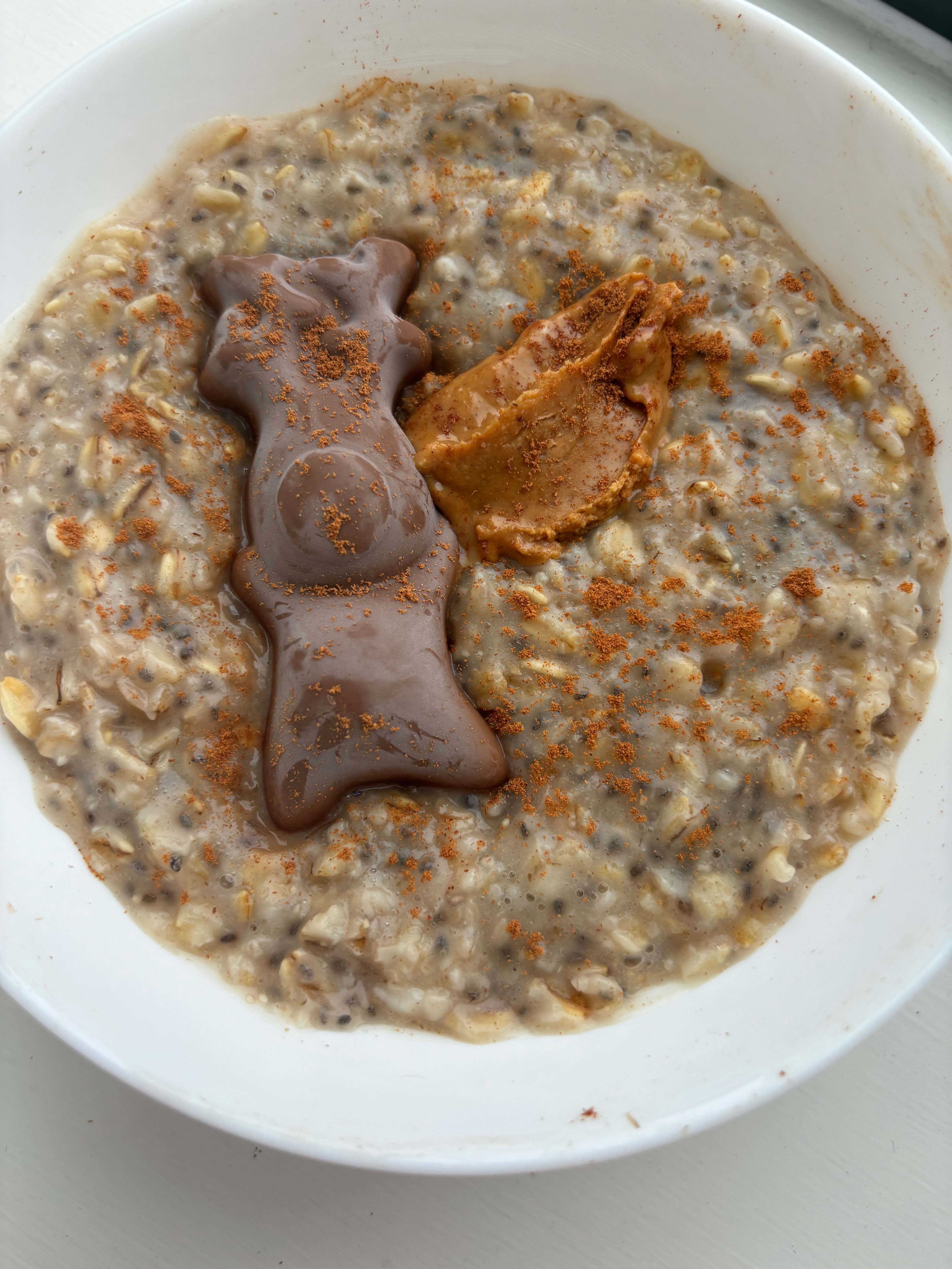 A bowl of porridge with chocolate and peanut butter on the top.