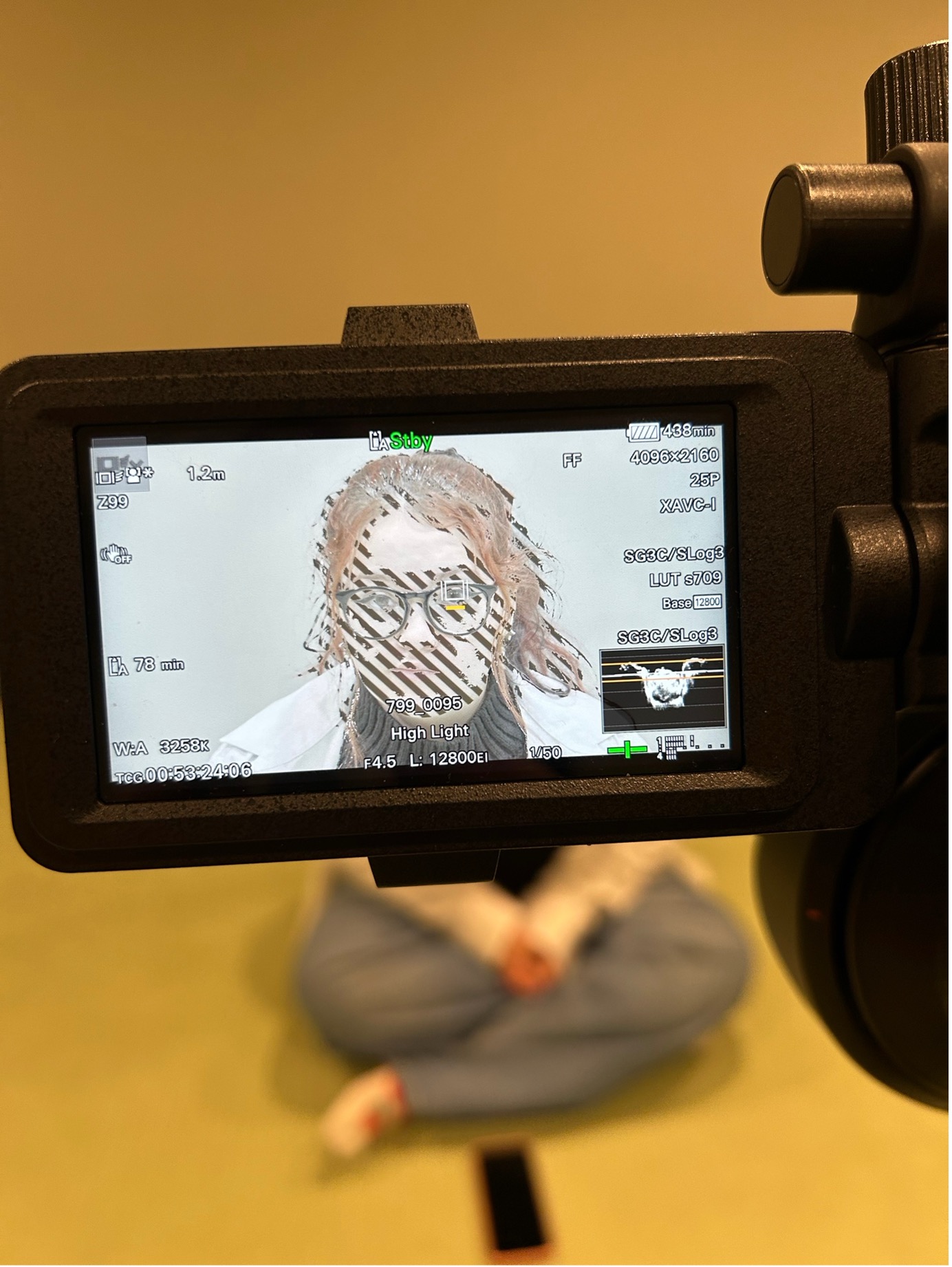 A camera screen focusing on a person's face who is sat in front of the camera.