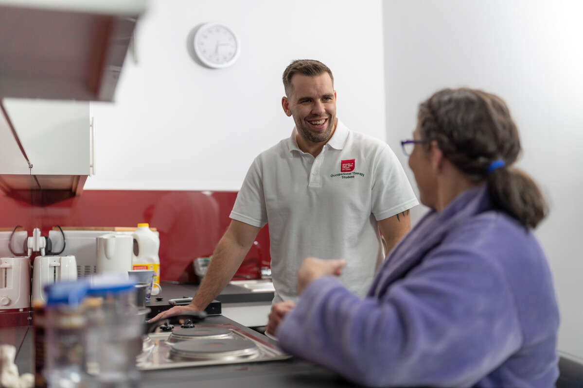 Occupational therapy student helping a patient in the kitchen of the community flat