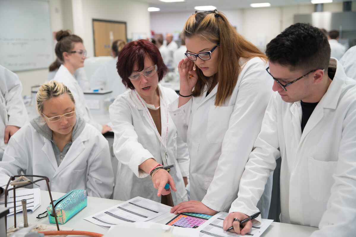 Chemistry students and teacher standing around a lab table