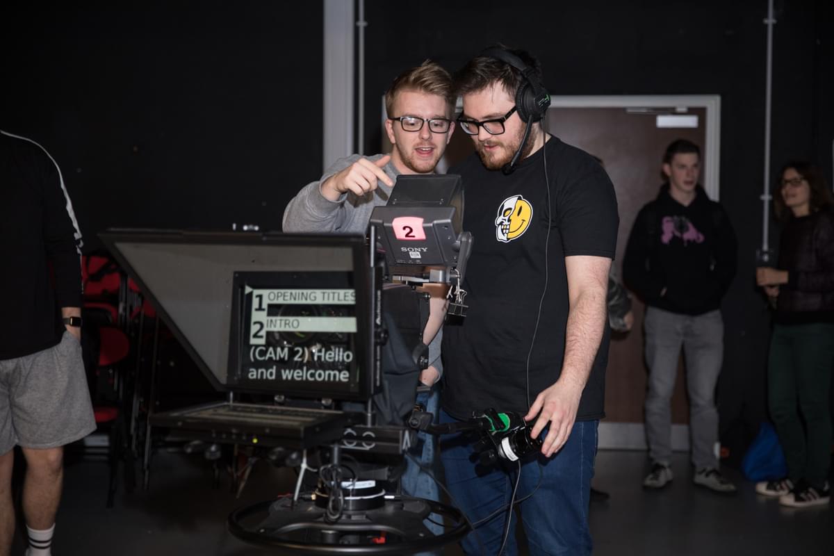 Two media production students using tv recording equipment in a tv studio