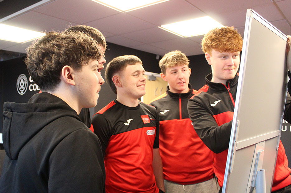 A group of football students gathered around a whiteboard during a task