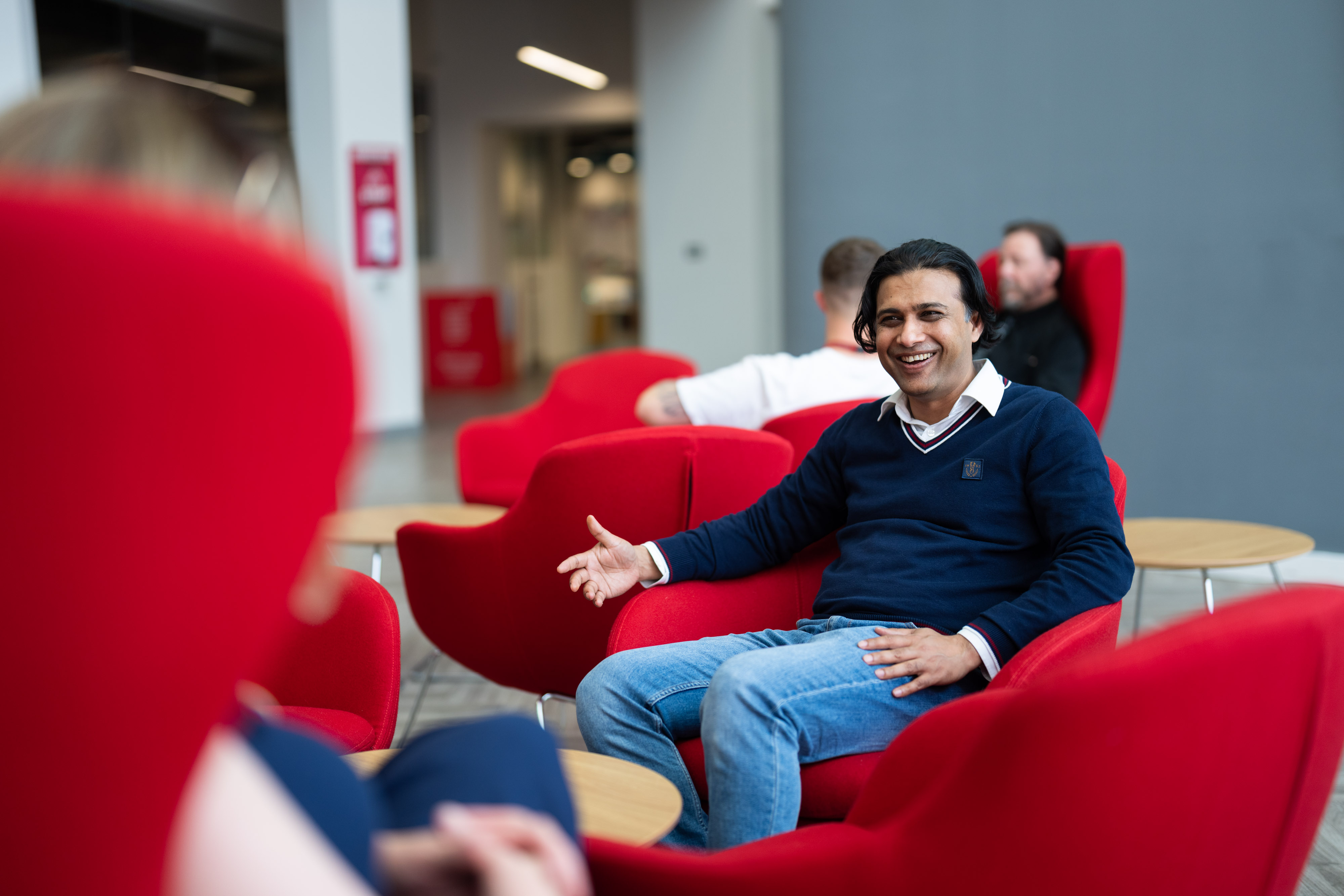 A member of staff smiling in the foyer of Cardiff Campus