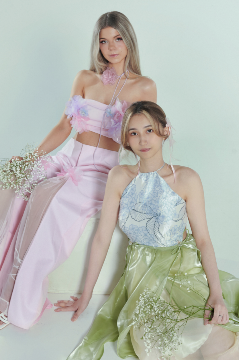 Two models wearing pastel coloured tops and skirts