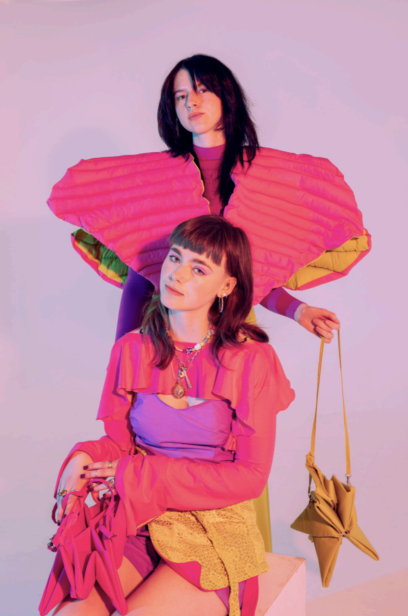 Two models with oversized vibrant pink and orange outfits