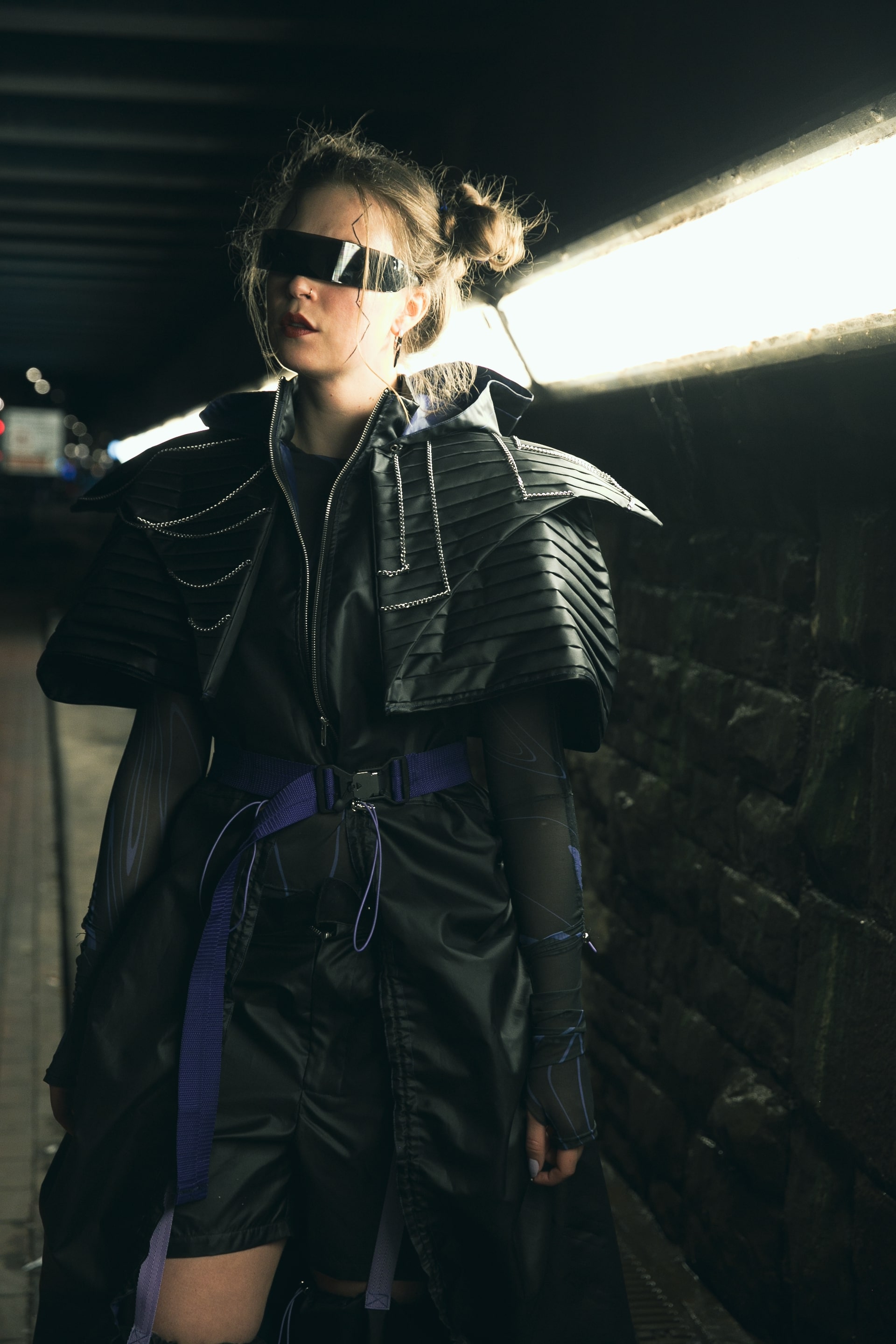 model wearing dark leather and sunglasses in a car park