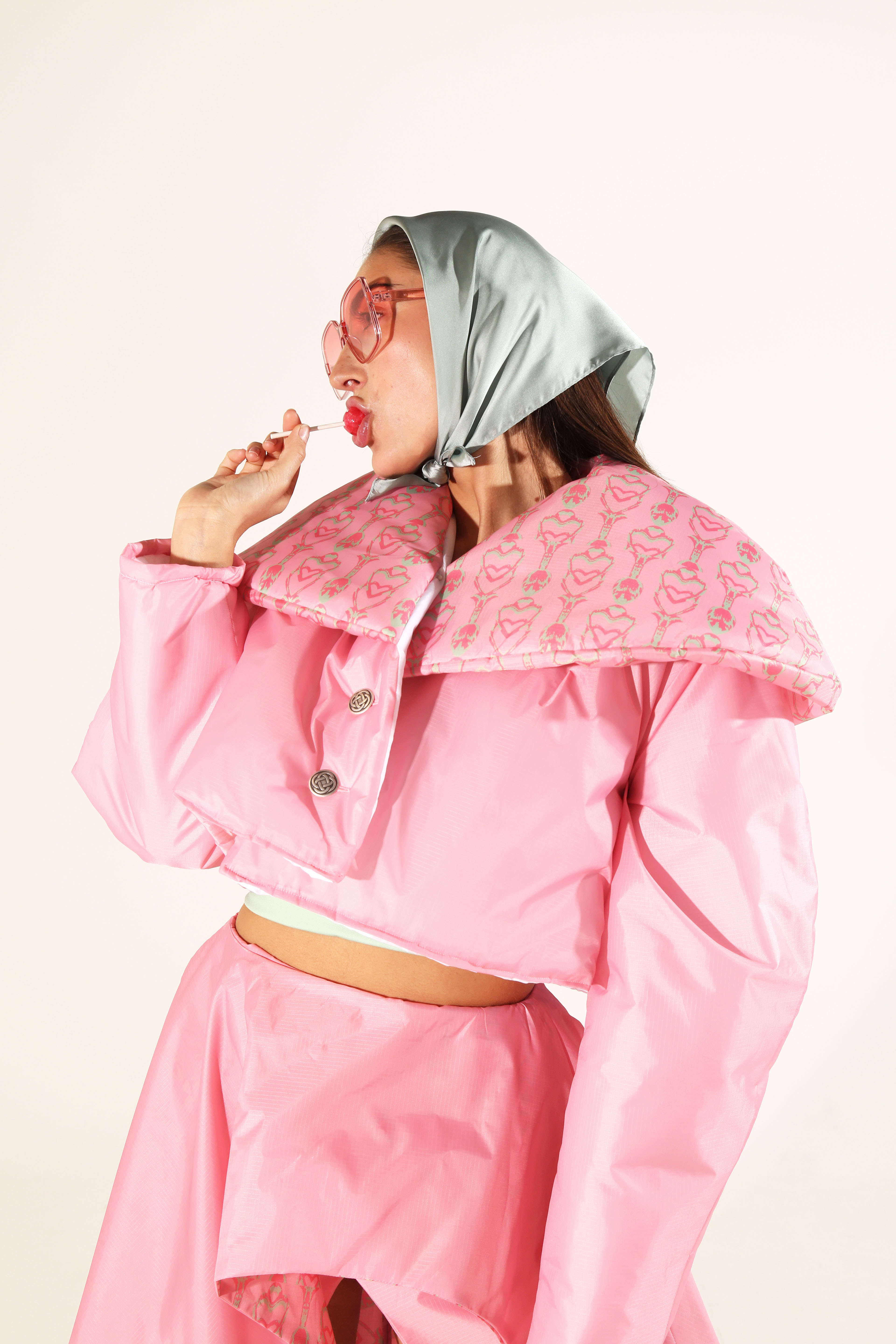 Model wearing headscarf and pink puffer jacket and trousers