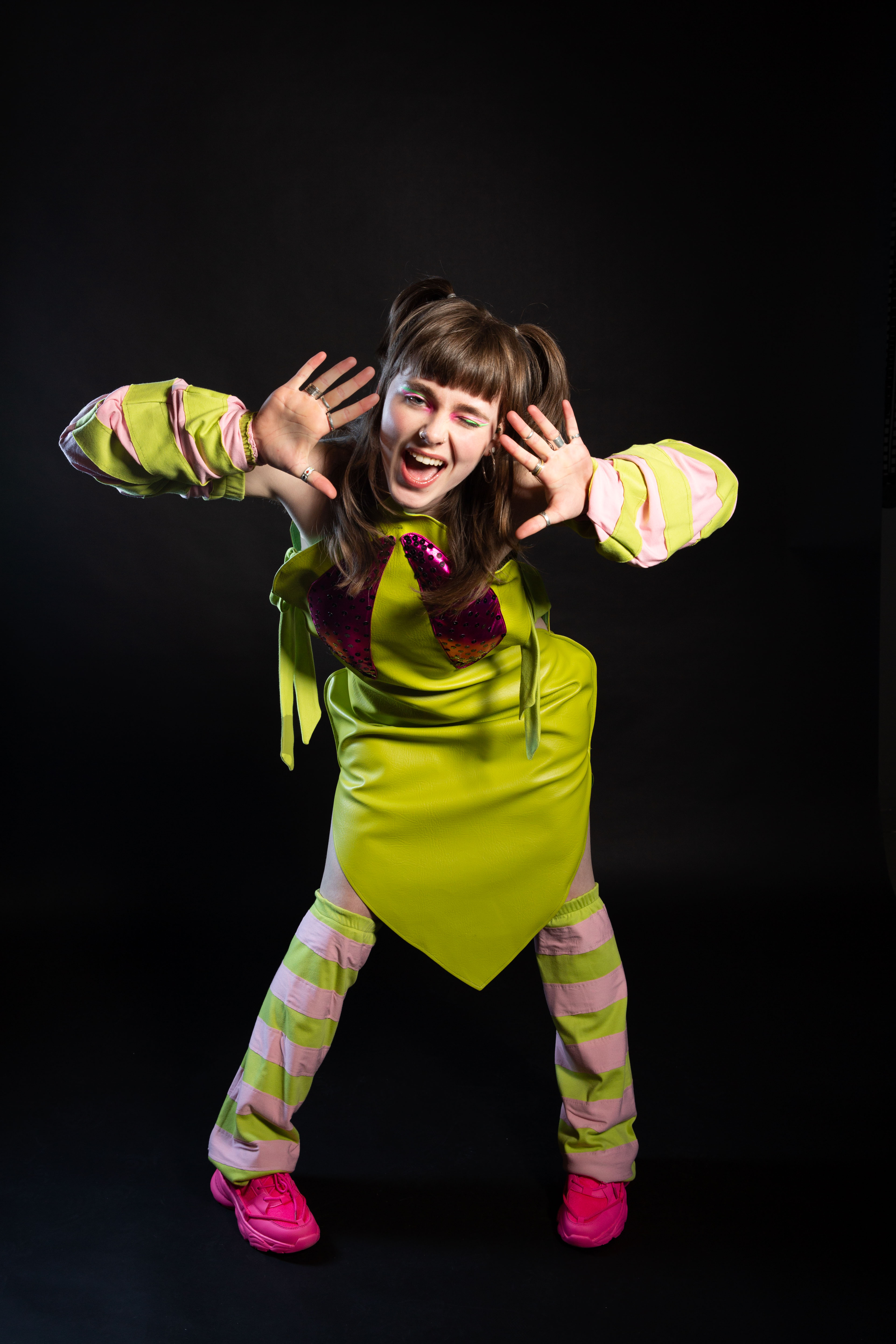 Model posing in a whimsical manner while wearing light/lime green clothes