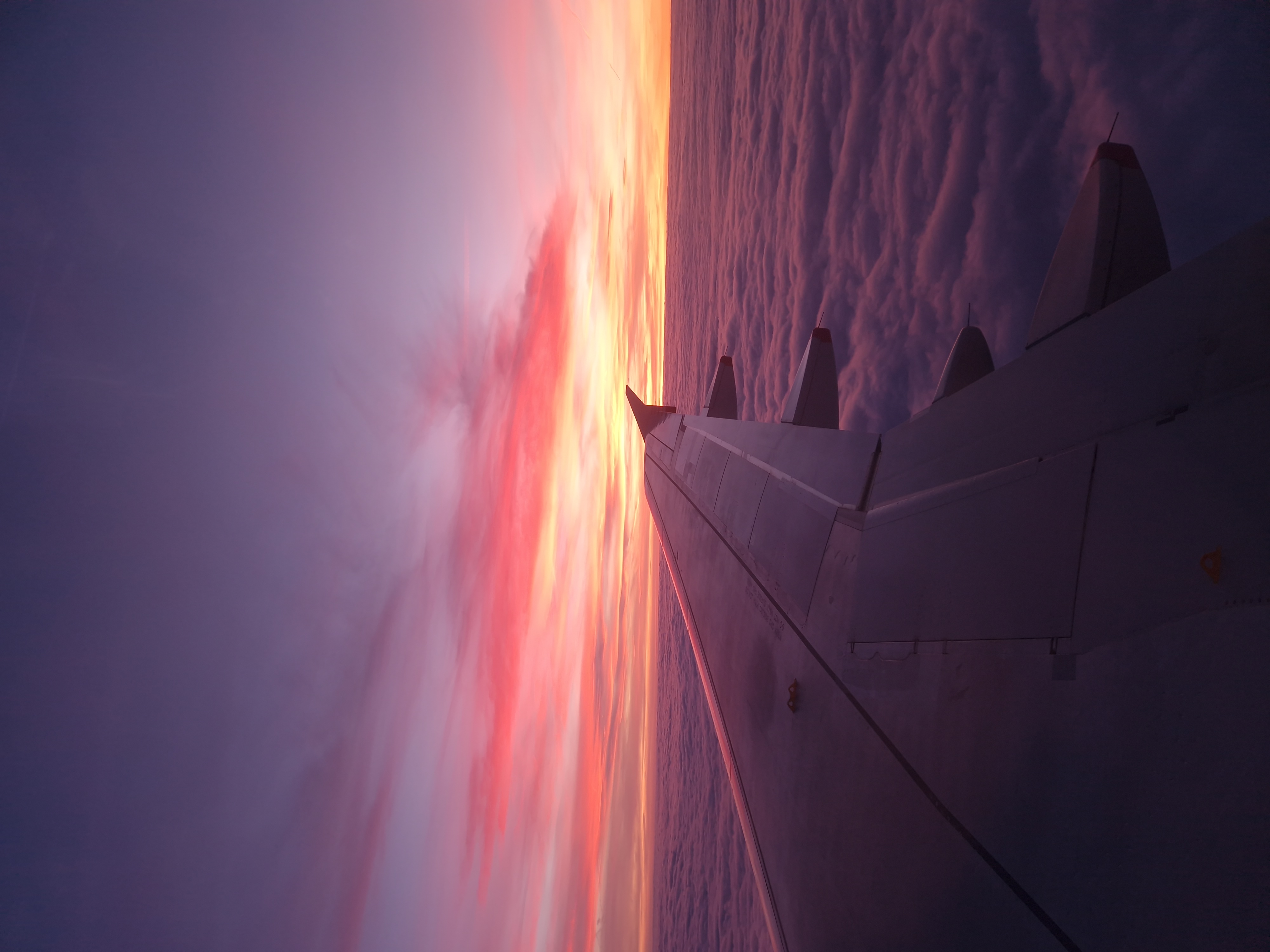 Sunset view from the window of an airplane with the wing of the plane