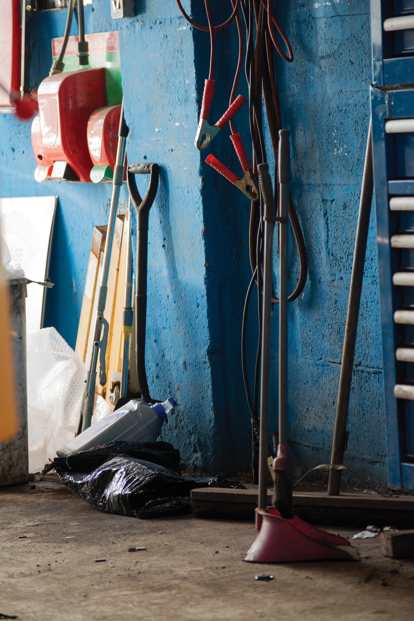 Cleaning equipment including a broom leaning on a blue wall