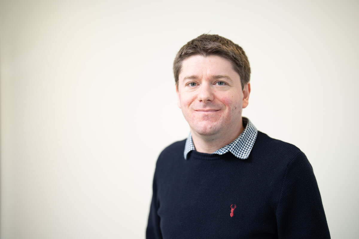 Associate Professor Christian Laycock smiling at the camera in front of a white backdrop