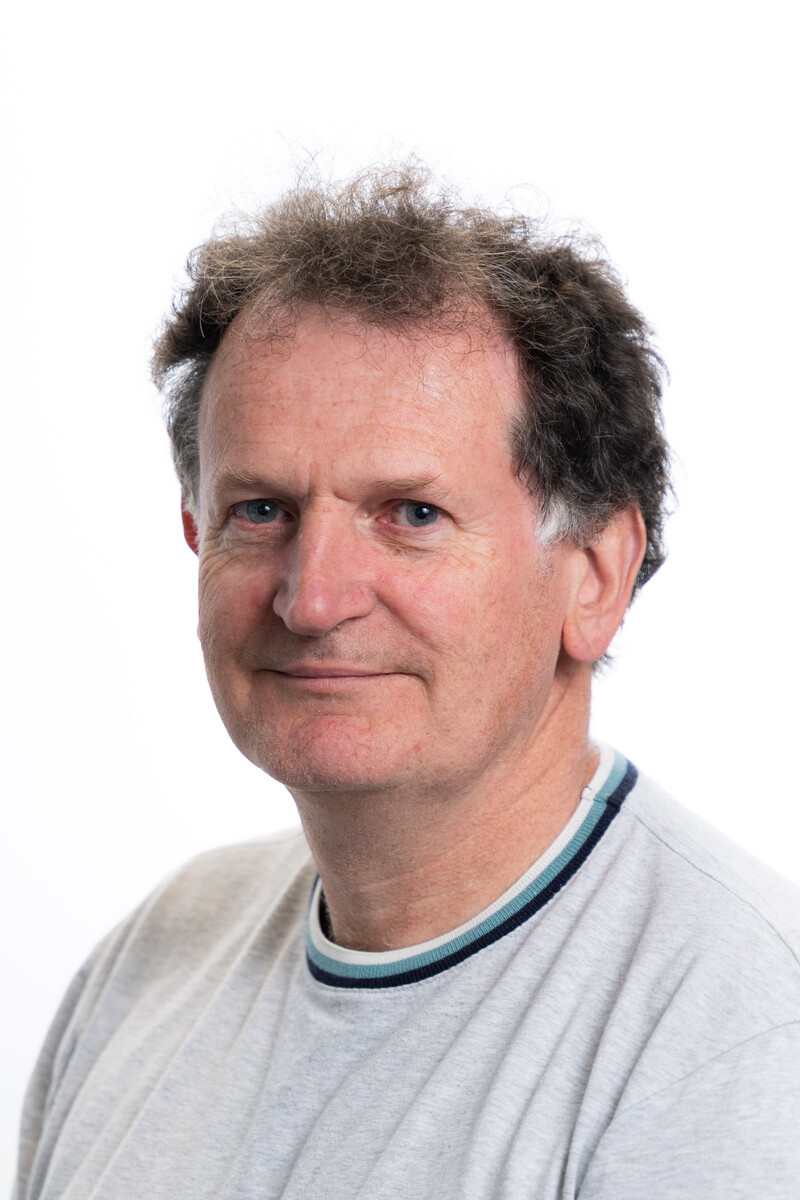 Dr Mitchel Langford smiles at the camera in front of a white backdrop