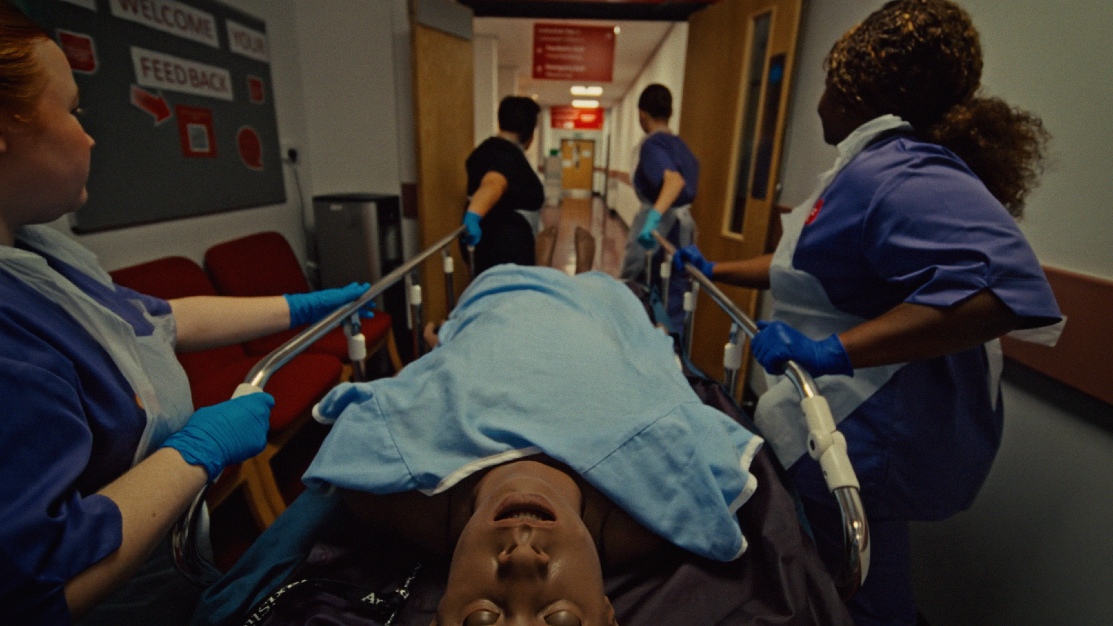 Point of view of a nurse helping to push a patient on a hospital bed, with the help of other student nurses