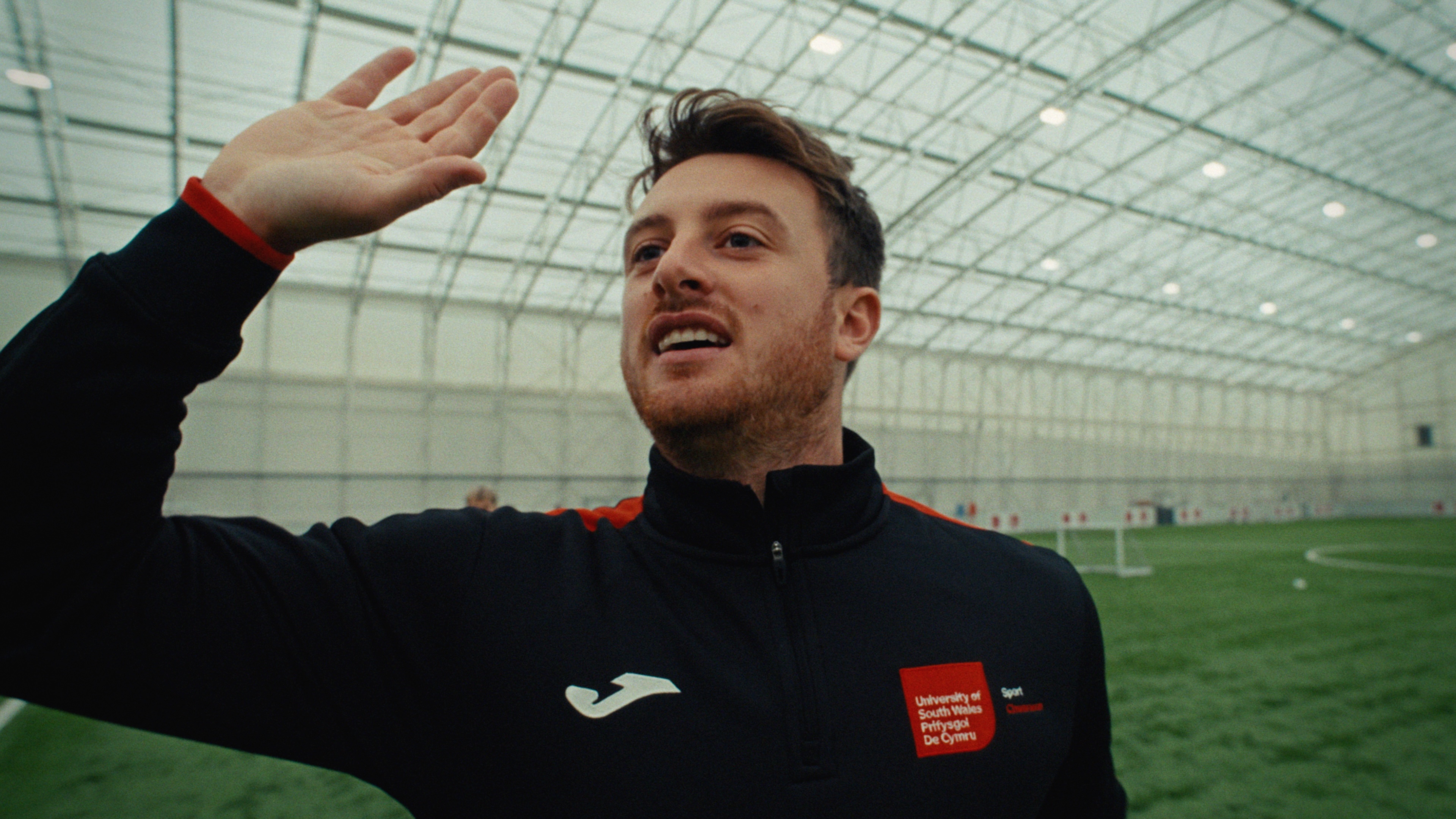Close up shot of sporting lecturer raising his hand whilst talking to students