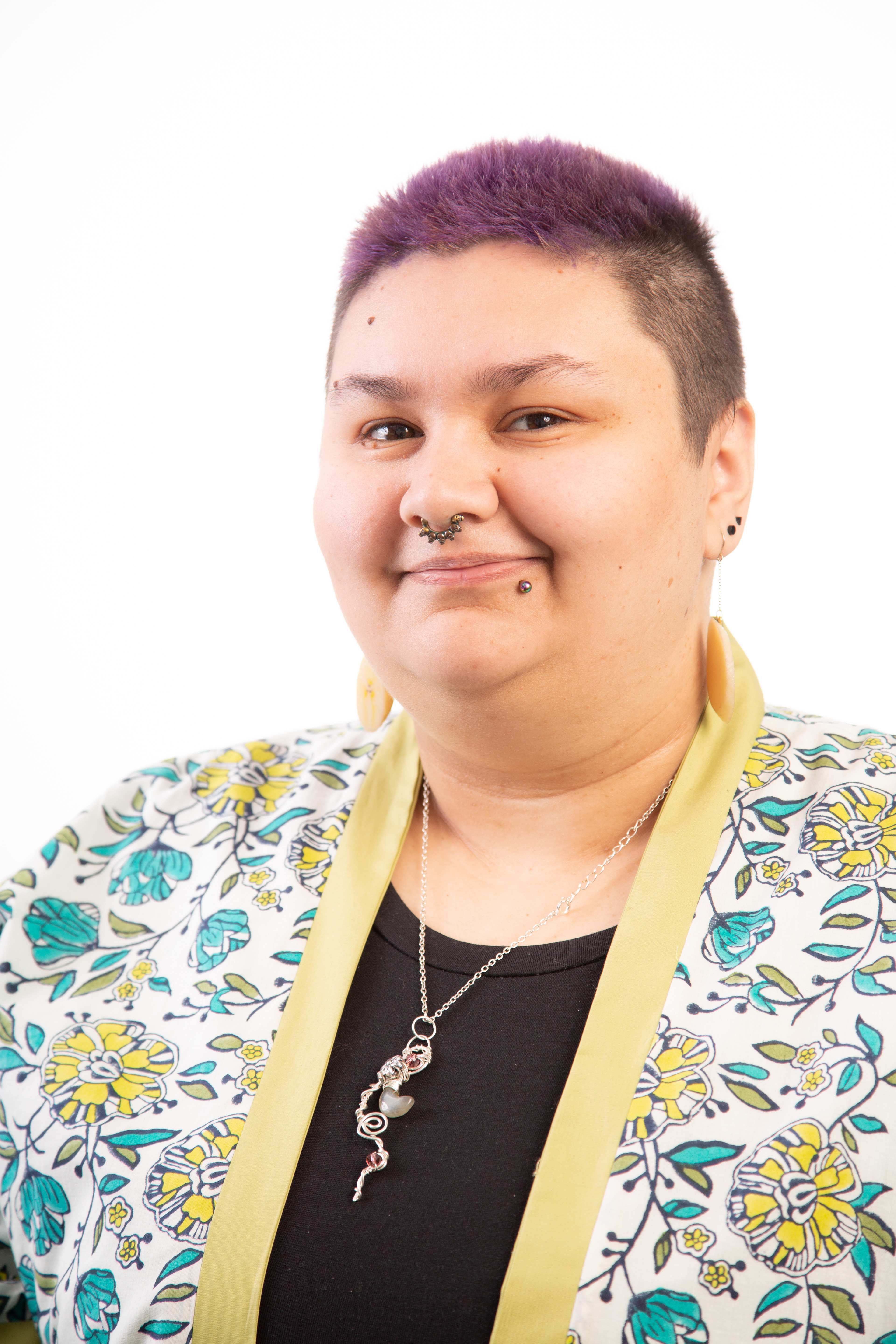 Fashion and design student Amber Jones smiles while looking into the camera in front of a white backdrop