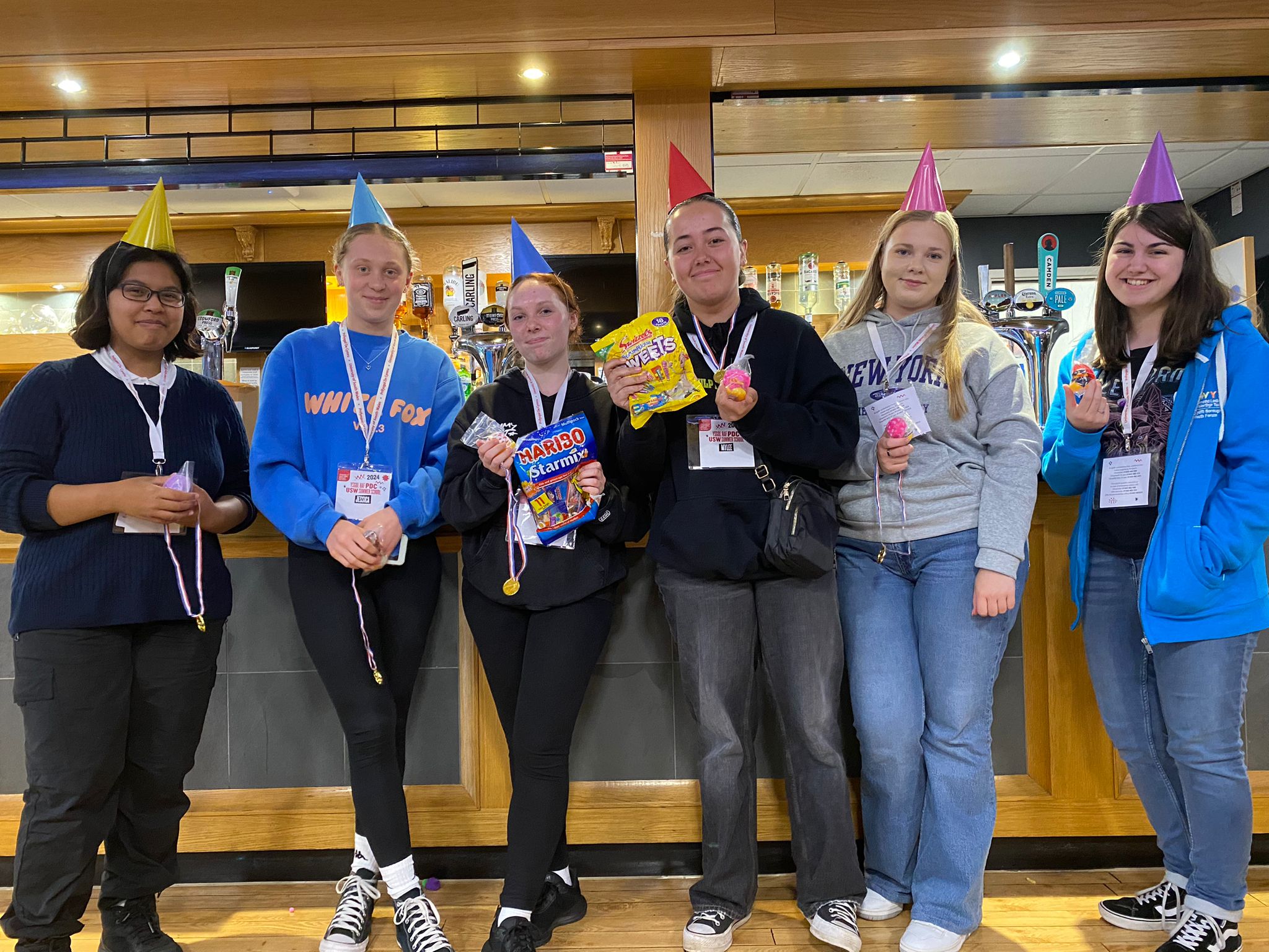 group of students wearing party hats standing in front of a bar