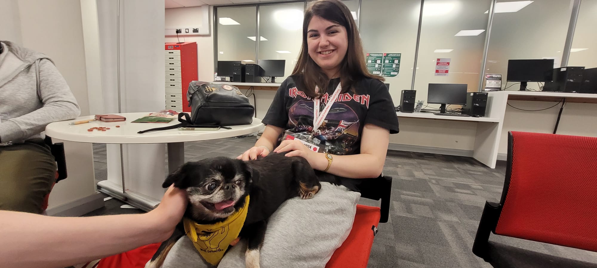 pupil holding a small black therapy dog