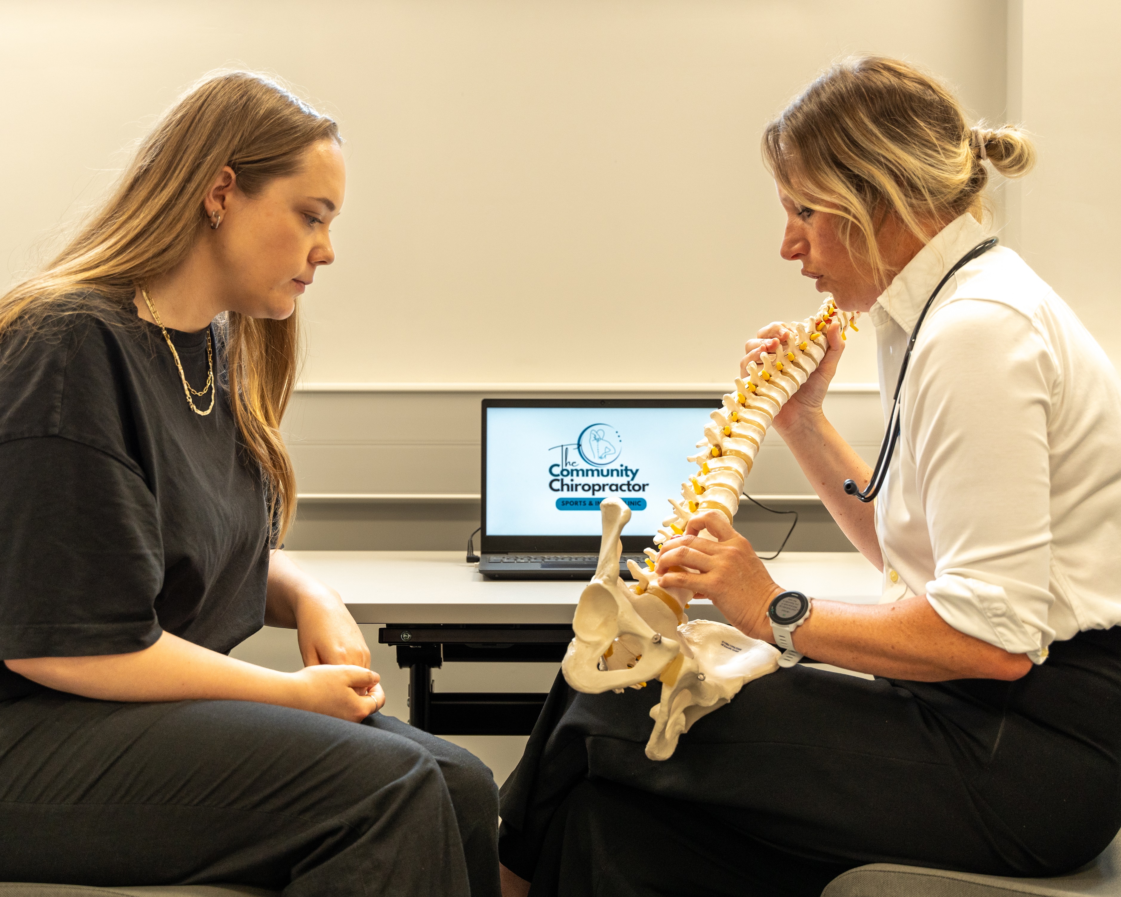 two females sitting, one holding and showing human bones