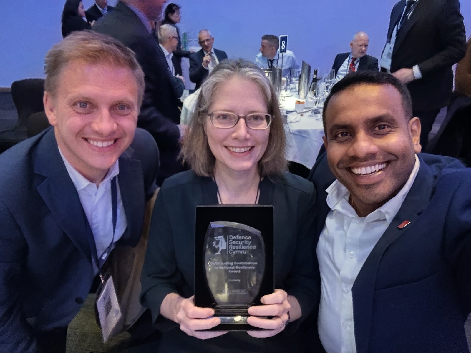 Rhys Driscoll, Jill Stewart and Leshan Uggalla sat at the award event posing with a glass trophy.