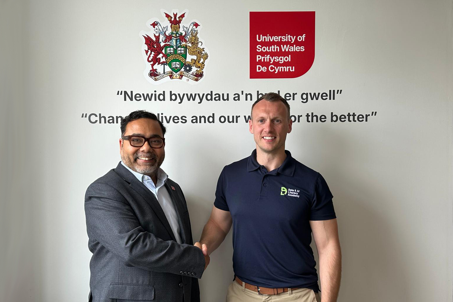 Representatives from the University of South Wales and the Data & AI Literacy Academy shake hands to mark a partnership.