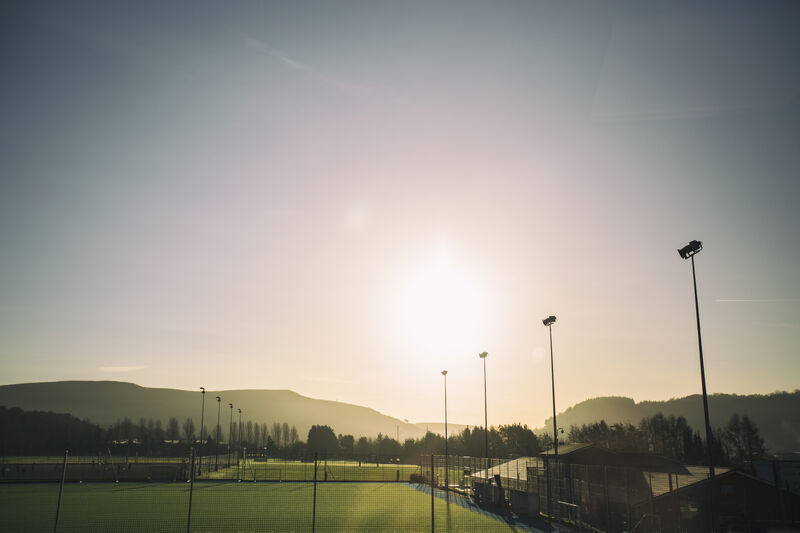 An outside shot of sport fields on a sunny day. There are mountains in the background.