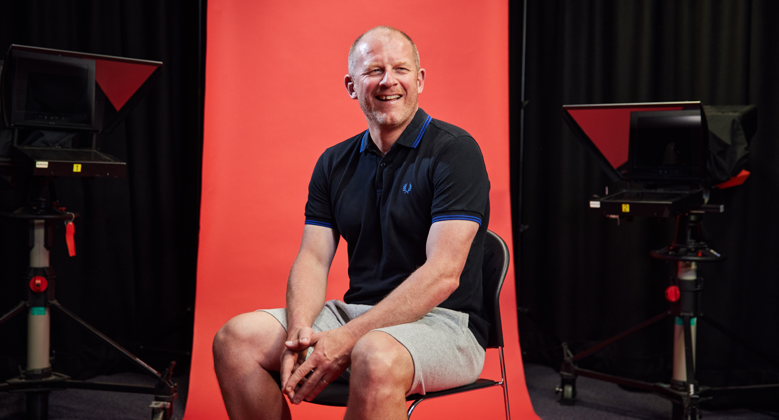 Staff sat in front of a red backdrop smiling